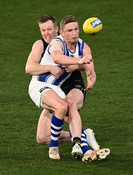 Jack Ziebell of the Kangaroos handballs whilst being tackled by Jack Riewoldt of the Tigers during the round 21 AFL match between Richmond Tigers and...