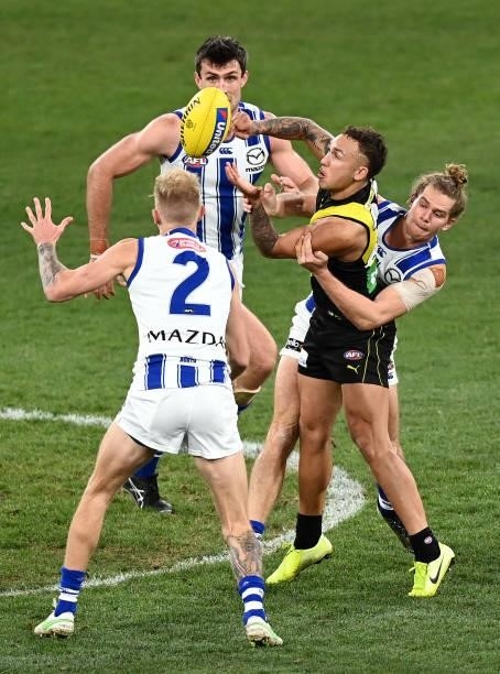 Shai Bolton of the Tigers handballs whilst being tackled by Jed Anderson of the Kangaroos during the round 21 AFL match between Richmond Tigers and...