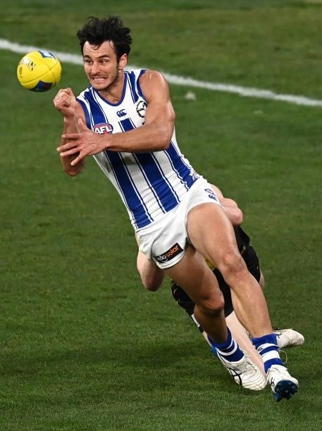 Robbie Tarrant of the Kangaroos handballs whilst being tackled during the round 21 AFL match between Richmond Tigers and North Melbourne Kangaroos at...