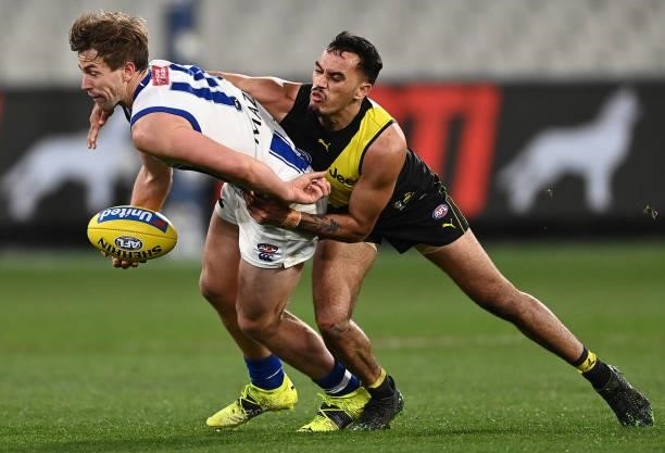 Trent Dumont of the Kangaroos handballs whilst being tackled by Sydney Stack of the Tigers during the round 21 AFL match between Richmond Tigers and...