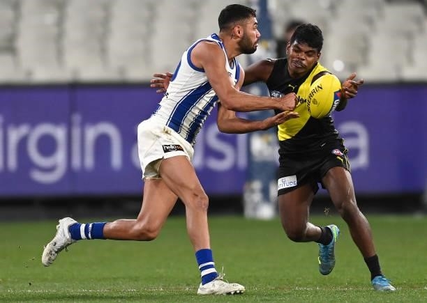Tarryn Thomas of the Kangaroos handballs whilst being tackled by Maurice Rioli of the Tigers during the round 21 AFL match between Richmond Tigers...