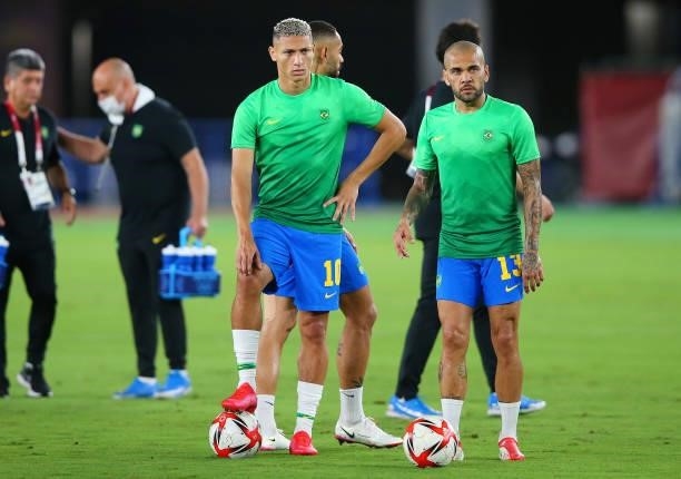 Richarlison and Dani Alves of Team Brazil look on as they warm up prior to the Men's Gold Medal Match between Brazil and Spain on day fifteen of the...