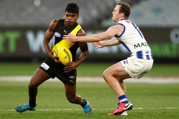 Maurice Rioli of the Tigers runs with the ball under pressure from Jack Mahony of the Kangaroos during the round 21 AFL match between Richmond Tigers...