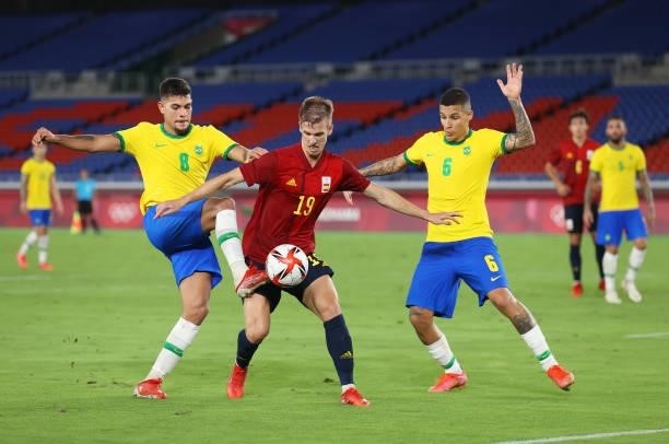 Dani Olmo of Team Spain battles for possession with Bruno Guimaraes and Guilherme Arana of Team Brazil during the Men's Gold Medal Match between...