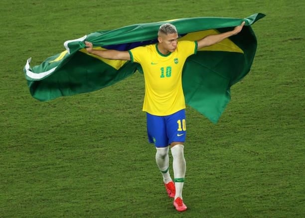 Richarlison of Team Brazil celebrates their side's victory with a flag of Brazil after the Men's Gold Medal Match between Brazil and Spain on day...