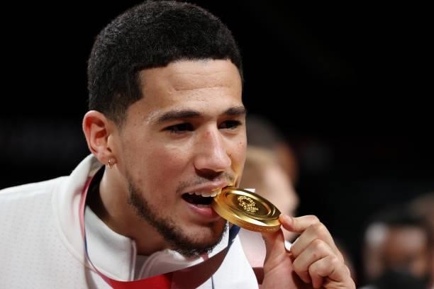 Devin Booker of Team United States bites his gold medal during the Men's Basketball medal ceremony on day fifteen of the Tokyo 2020 Olympic Games at...