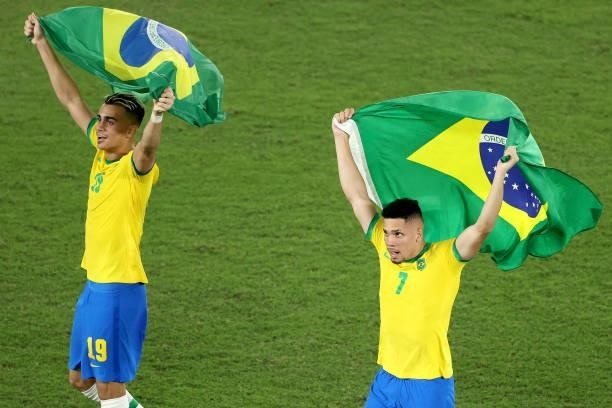 Reinier and Paulinho of Team Brazil celebrate their side's victory with flags of Brazil after the Men's Gold Medal Match between Brazil and Spain on...
