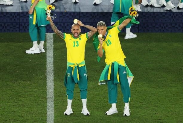 Gold medalists Richarlison and Dani Alves of Team Brazil pose with their gold medals during the Men's Football Competition Medal Ceremony on day...