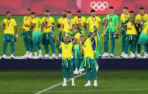 Gold medalists Richarlison and Dani Alves of Team Brazil pose with their gold medals during the Men's Football Competition Medal Ceremony on day...