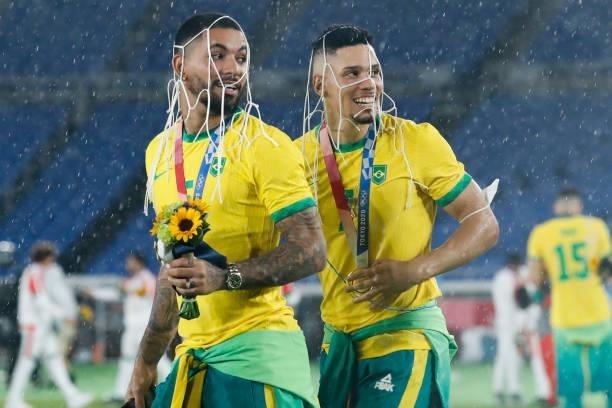Douglas Luiz, Paulinho of Brazil celebrate after the award ceremony of the Men's Gold Medal Match between Brazil and Spain on day fifteen of the...