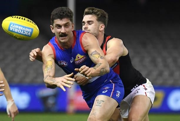 Tom Liberatore of the Bulldogs handballs whilst being tackled during the round 21 AFL match between Western Bulldogs and Essendon Bombers at Marvel...