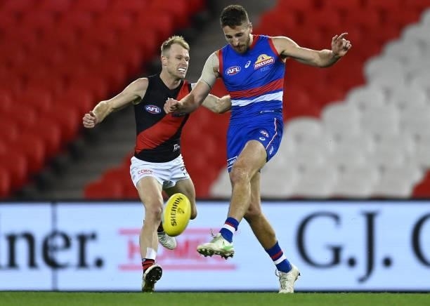 Marcus Bontempelli of the Bulldogs kicks whilst being tackled by Nick Hind of the Bombers during the round 21 AFL match between Western Bulldogs and...