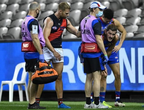 Jake Stringer of the Bombers helps Josh Bruce of the Bulldogs up after he grabbed at his knee during the round 21 AFL match between Western Bulldogs...