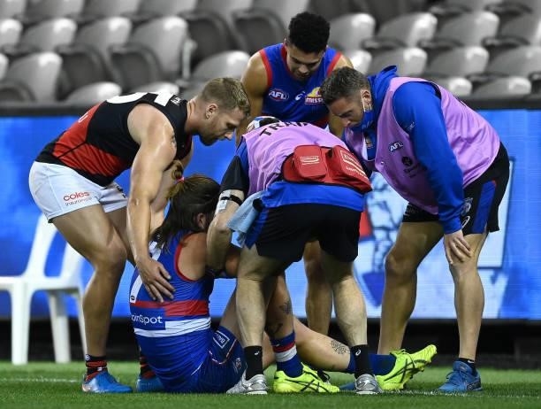 Jake Stringer of the Bombers helps Josh Bruce of the Bulldogs up after he grabbed at his knee during the round 21 AFL match between Western Bulldogs...
