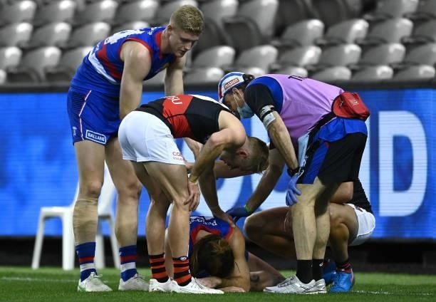 Josh Bruce of the Bulldogs is consoled by Tim English of the Bulldogs and Nick Hind of the Bombers after injuring his knee during the round 21 AFL...