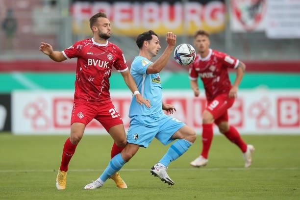 Nicolas Hoefler of SC Freiburg is tackled by David Kopacz of Wuerzburger Kickers during the DFB Cup first round match between Würzburger Kickers and...