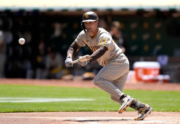 Adam Frazier of the San Diego Padres bunts the ball against the Oakland Athletics in the top of the first inning at RingCentral Coliseum on August...