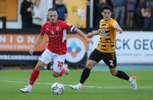 Jack Payne of Swindon Town moves with the ball away from George Williams of Cambridge United during the Carabao Cup 1st Round match between Cambridge...
