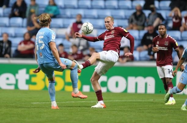 Mitch Pinnock of Northampton Town looks to play the ball watched by Delan Drysdale of Coventry City during the Carabao Cup 1st Round match between...