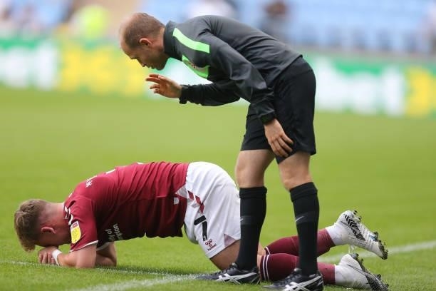 Fourth Official Richard Morris looks on as Sam Hoskins of Northampton Town lays injured during the Carabao Cup 1st round match between Coventry City...