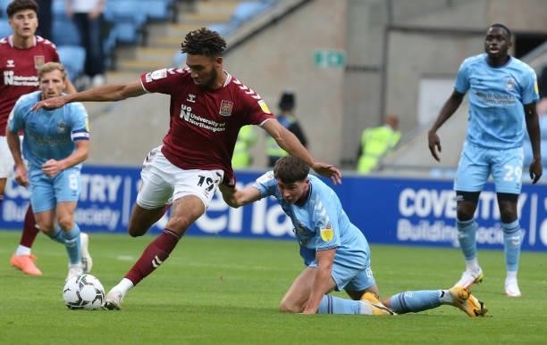 Kion Etete of Northampton Town looks to play the ball while being held by Ryan Howley of Coventry City during the Carabao Cup 1st round match between...