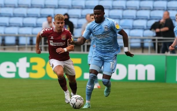 Bright Enobakhare of Coventry City moves with the ball away from Sam Hoskins of Northampton Town during the Carabao Cup 1st round match between...