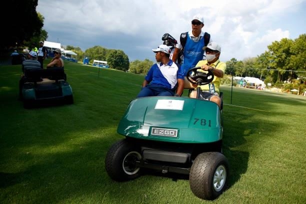 Hideki Matsuyama of Japan and caddie Shota Hayafuji are driven off the course near the 15th fairway during a delay due to inclement weather during...