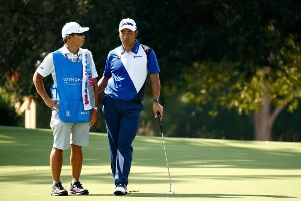 Hideki Matsuyama of Japan and caddie Shota Hayafuji wait on the 14th green during the first round of the Wyndham Championship at Sedgefield Country...