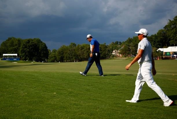Hideki Matsuyama of Japan and Rickie Fowler of the United States walk off the course on the 15th hole due to a weather delay during the first round...
