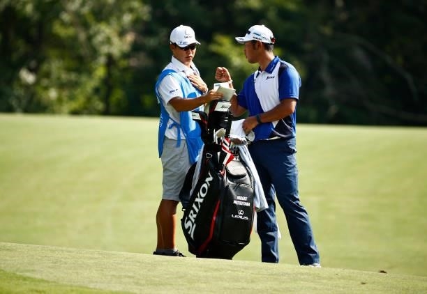Hideki Matsuyama of Japan and caddie Shota Hayafuji wait on the 14th hole during the first round of the Wyndham Championship at Sedgefield Country...