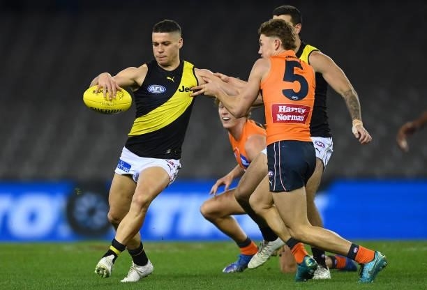 Dion Prestia of the Tigers kicks whilst being tackled by Tanner Bruhn of the Giants during the round 22 AFL match between Greater Western Sydney...