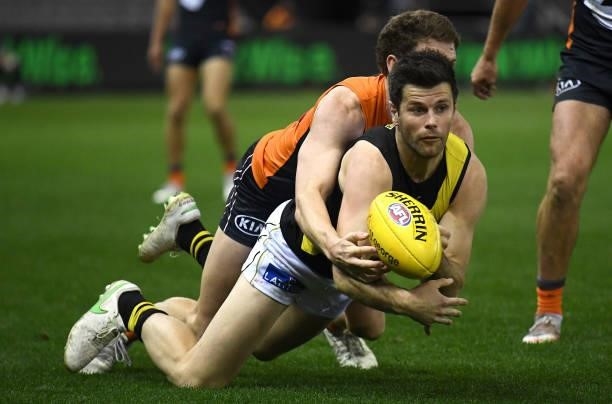 Trent Cotchin of the Tigers handballs whilst being tackled during the round 22 AFL match between Greater Western Sydney Giants and Richmond Tigers at...