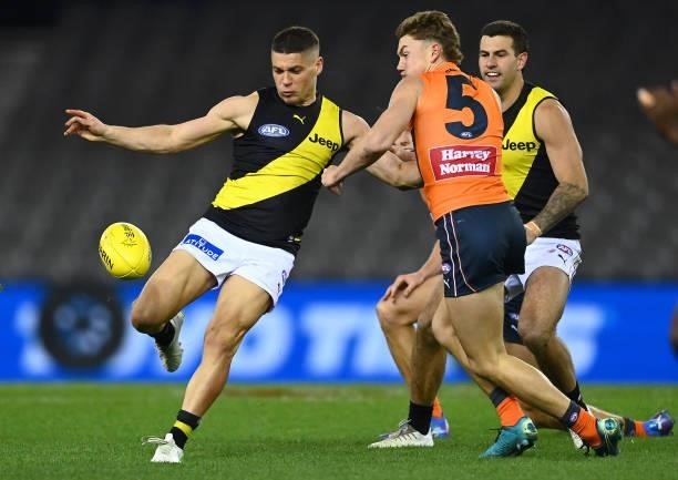 Dion Prestia of the Tigers kicks whilst being tackled by Tanner Bruhn of the Giants during the round 22 AFL match between Greater Western Sydney...