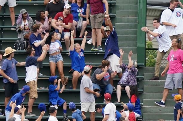 A fan catches the home run ball hit by Luis Urias of the Milwaukee Brewers during the seventh inning of a game against the Chicago Cubs at Wrigley...