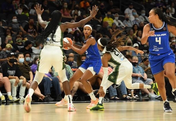 Jasmine Thomas of the Connecticut Sun looks to pass the ball while being defended by Jordin Canada and Ezi Magbegor of the Seattle Storm during the...