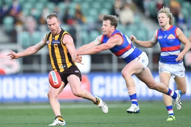 Tom Mitchell of the Hawks is tackled by Lachie Hunter of the Bulldogs during the round 22 AFL match between Hawthorn Hawks and Western Bulldogs at...