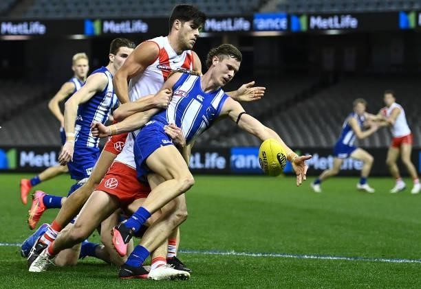 Charlie Comben of the Kangaroos kicks whilst being tackled during the round 22 AFL match between North Melbourne Kangaroos and Sydney Swans at Marvel...