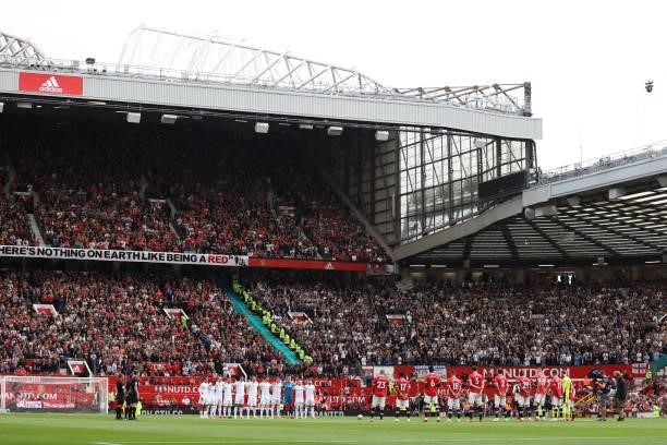 Players stand for a minutes applause for the players and staff who have lost their lives over the last year prior to the Premier League match between...