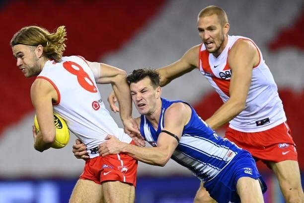 James Rowbottom of the Swans handballs whilst being tackled by Kayne Turner of the Kangaroos during the round 22 AFL match between North Melbourne...