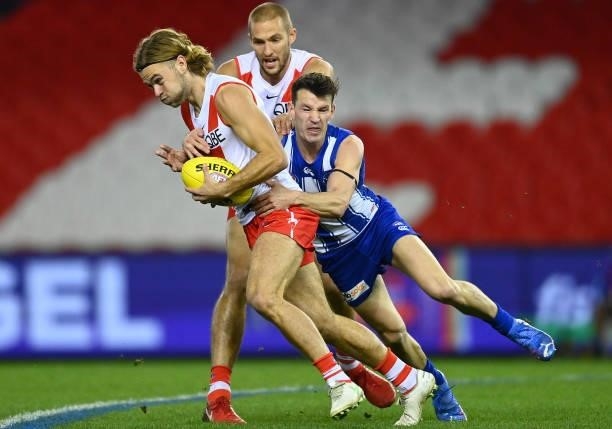 James Rowbottom of the Swans handballs whilst being tackled by Kayne Turner of the Kangaroos during the round 22 AFL match between North Melbourne...