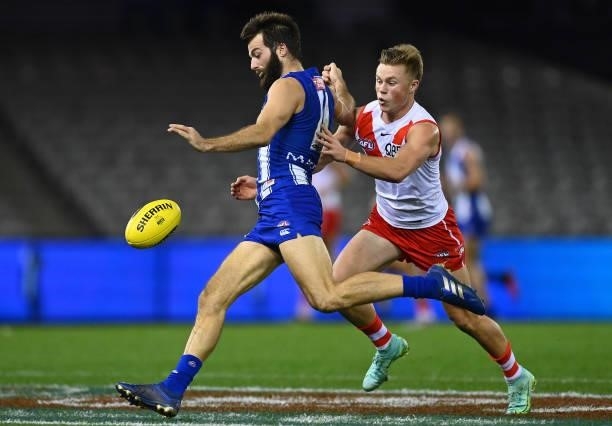 Luke McDonald of the Kangaroos kicks whilst being tackled by Braeden Campbell of the Swans during the round 22 AFL match between North Melbourne...