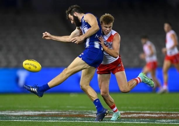 Luke McDonald of the Kangaroos kicks whilst being tackled by Braeden Campbell of the Swans during the round 22 AFL match between North Melbourne...