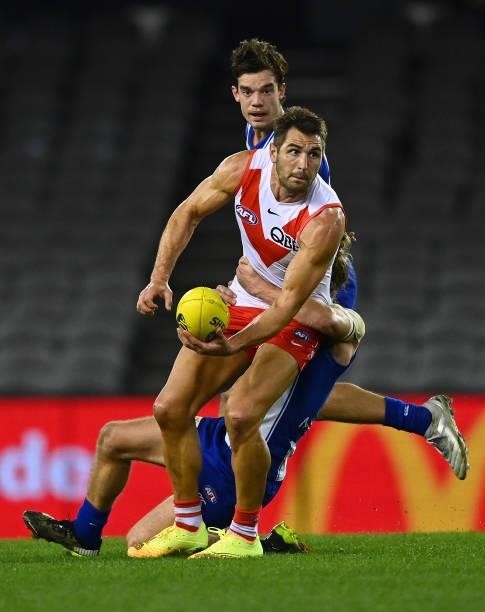 Josh P. Kennedy of the Swans handballs whilst being tackled by Jed Anderson of the Kangaroos during the round 22 AFL match between North Melbourne...