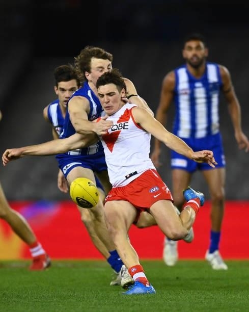 Errol Gulden of the Swans kicks whilst being tackled by Nick Larkey of the Kangaroos during the round 22 AFL match between North Melbourne Kangaroos...