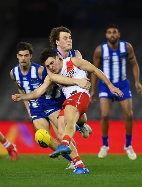 Errol Gulden of the Swans kicks whilst being tackled by Nick Larkey of the Kangaroos during the round 22 AFL match between North Melbourne Kangaroos...