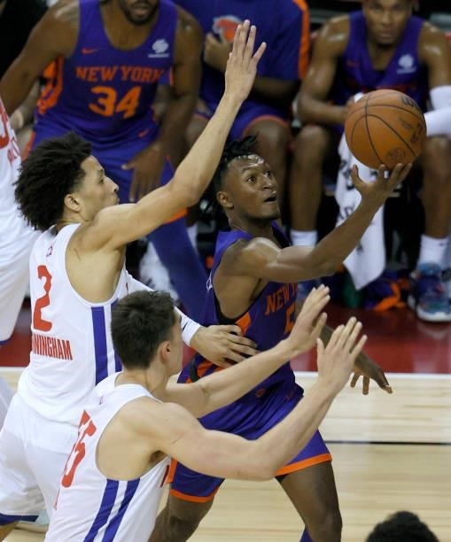 Immanuel Quickley of the New York Knicks drives to the basket against Cade Cunningham and Luka Garza of the Detroit Pistons during the 2021 NBA...