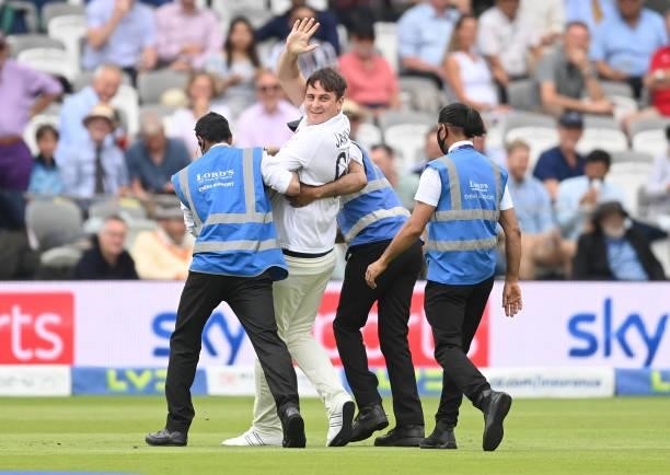 Pitch intruder dressed as a cricketer waves as he is escorted off the field during the third day of the 2nd LV= Test match between England and India...