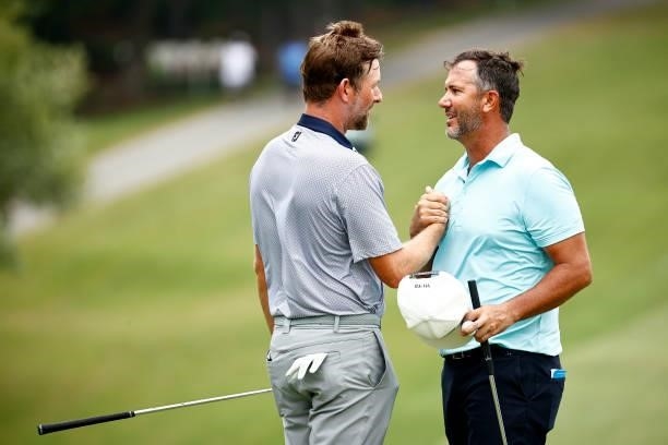 Webb Simpson of the United States and Scott Piercy of the United States shake hands on the 18th green during the third round of the Wyndham...
