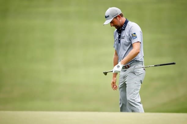 Webb Simpson of the United States looks at his club after a chip shot on the 18th green during the third round of the Wyndham Championship at...