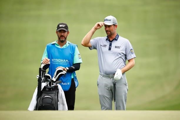 Webb Simpson of the United States acknowledges the crowd as he waits with caddie Paul Tesori on the 18th hole during the third round of the Wyndham...